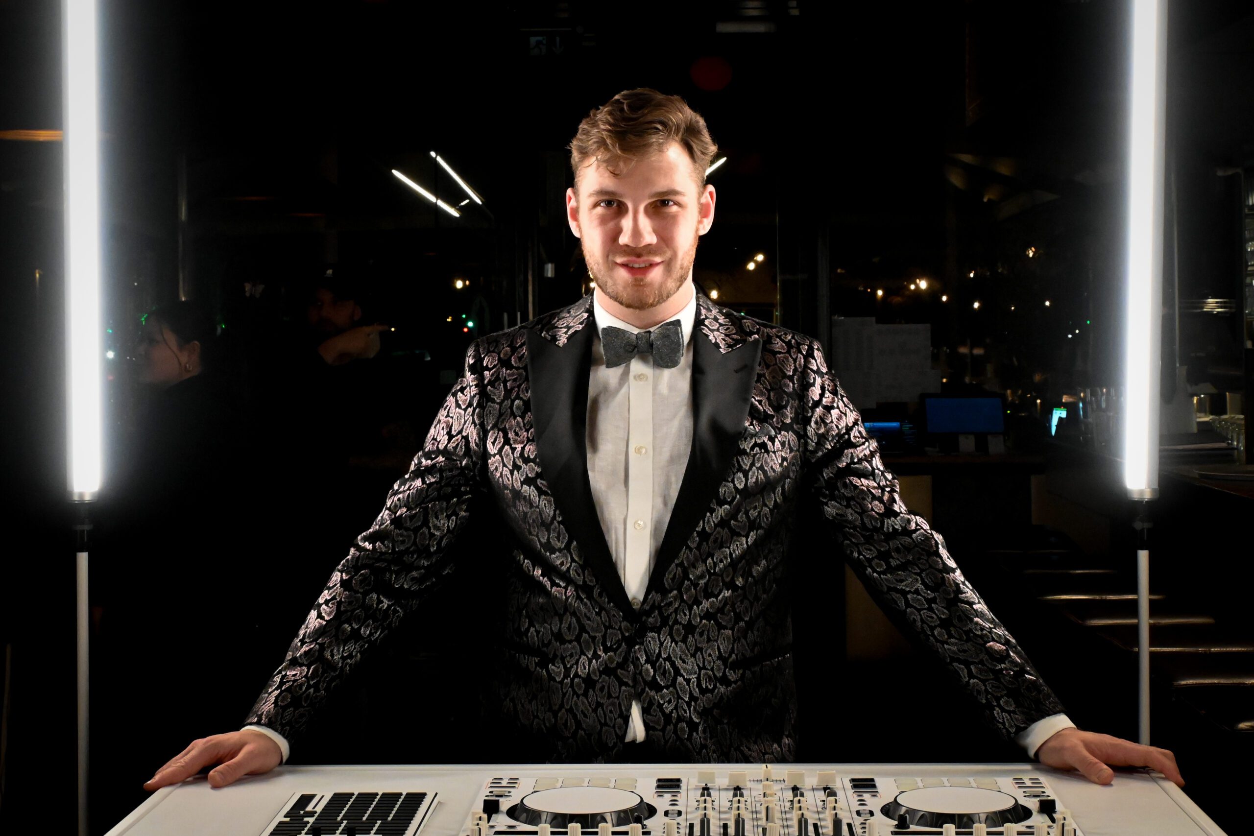 DJ Karl im Anzug am DJ-Pult mit Controller und Lichtsetup bei einem professionellen Fotoshooting